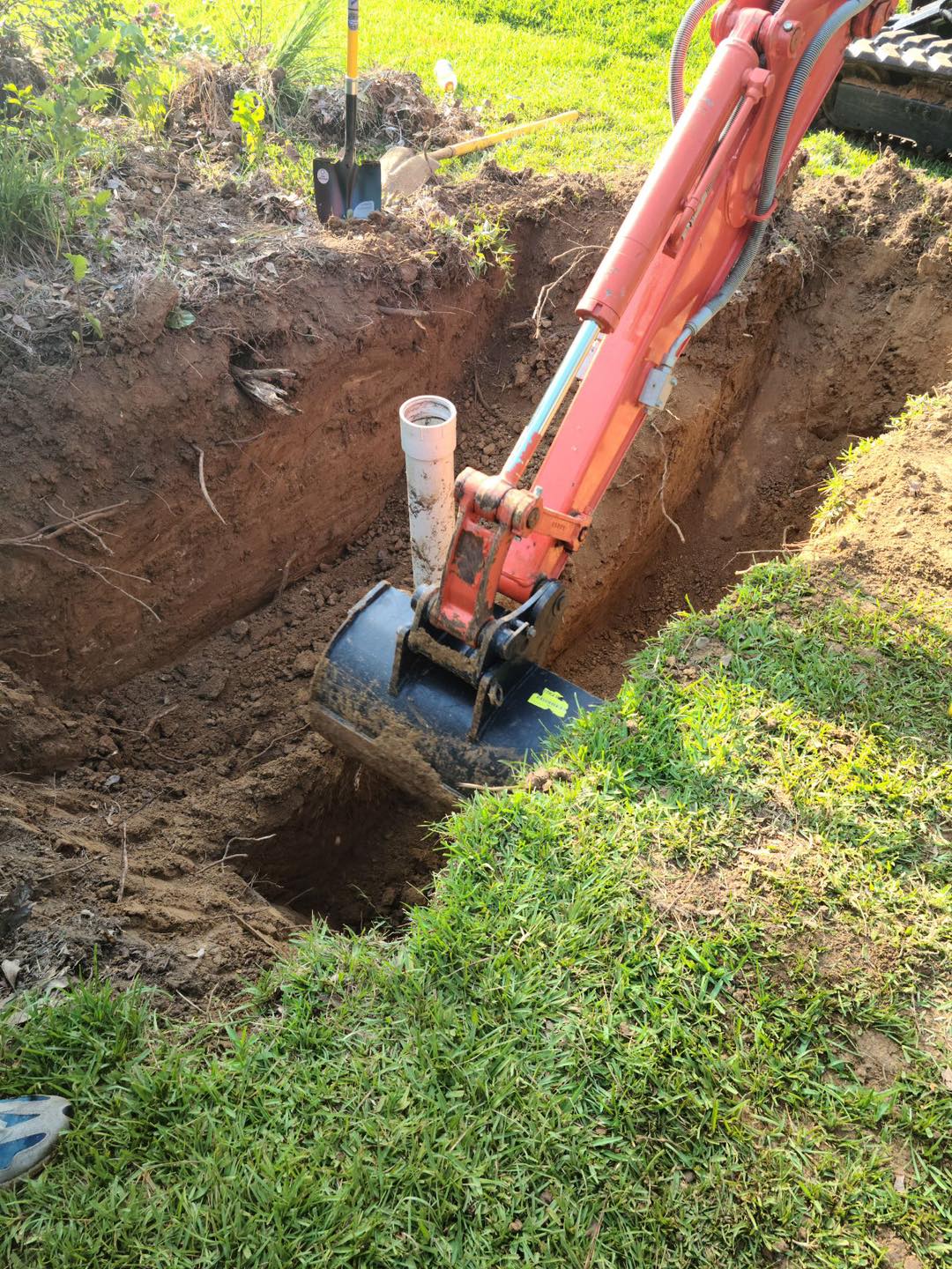 Excavator digging a deep trench to set a sewer cleanout